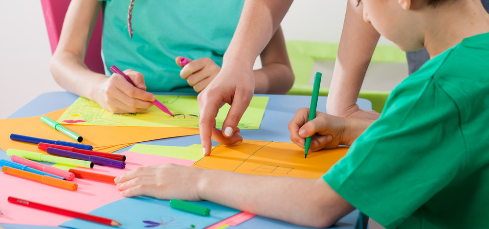 Children develop their creativity by drawing with art teacher
