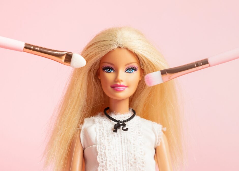 a barbie doll with makeup brushes by its face