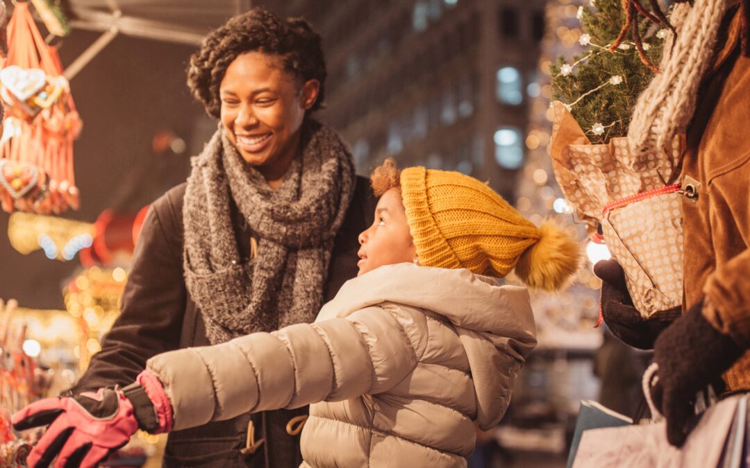 a family bundled up for winter looking through windows at holiday displays