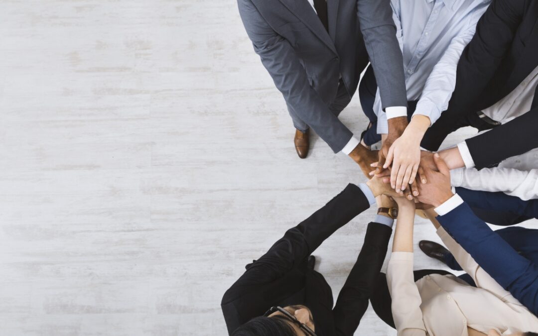 a group of people standing in a circle with their hands in the middle