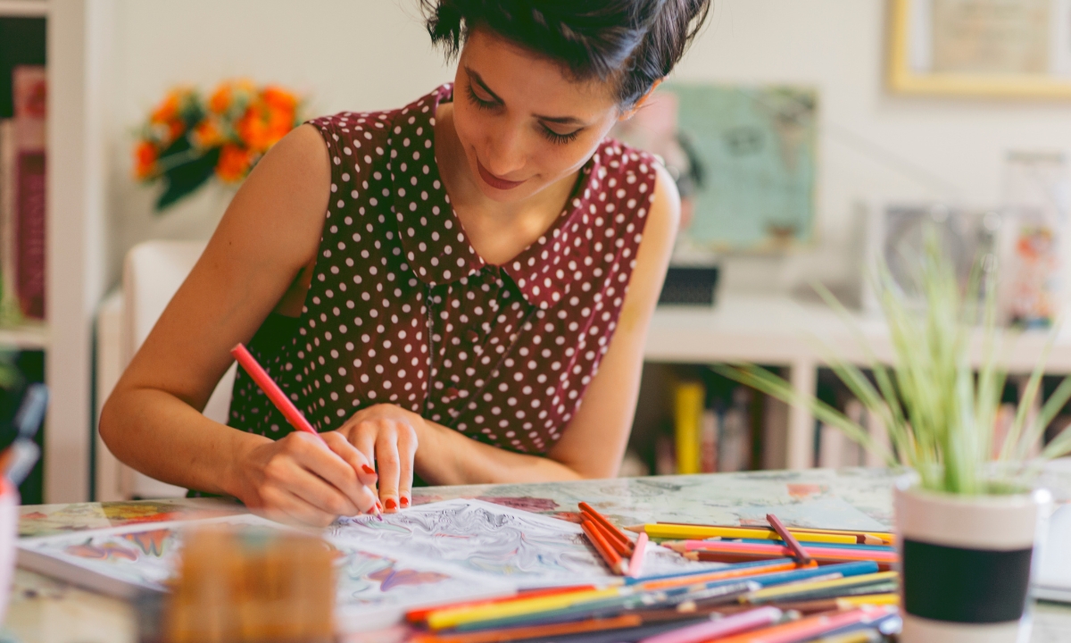 an adult coloring in a book at their desk